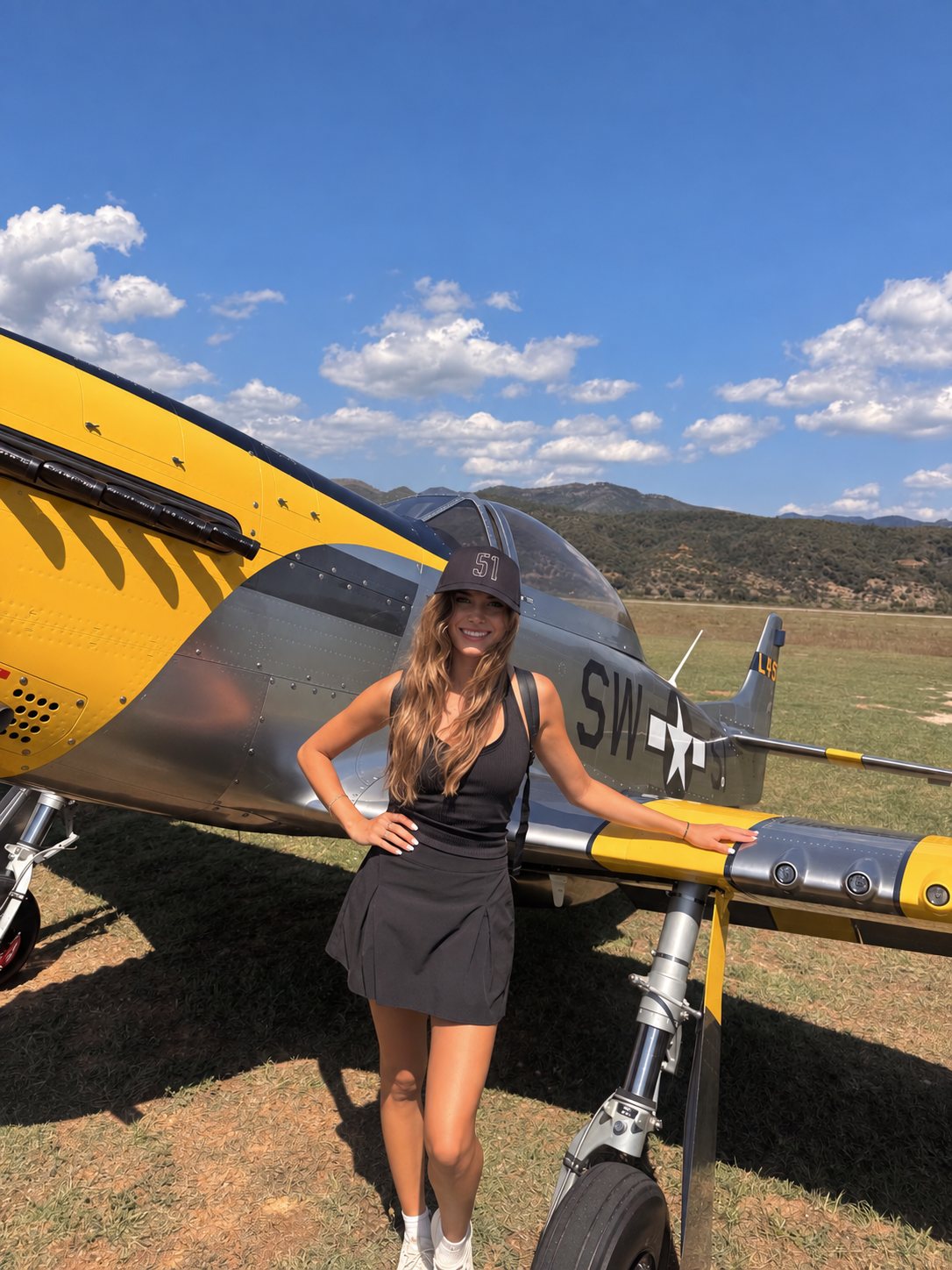 Mikayla beside a P-51 Mustang on a grass strip