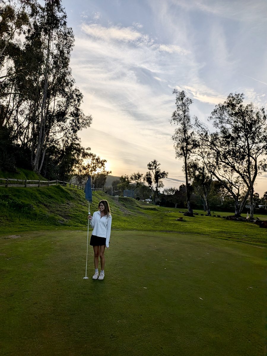 Standing on the green at sunset holding the flagstick and the ball